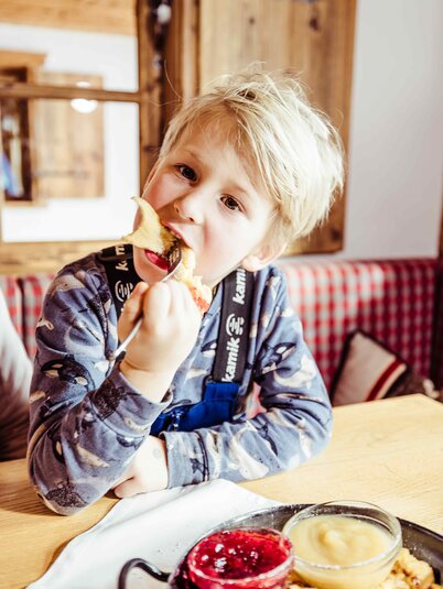 Ein Junge isst genüsslich seinen Kaiserschmarrn auf der Skihütte in Alpbach | © Alpbachtal Tourismus |shootandstyle 