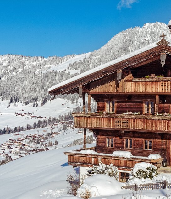 Auf dem Bild zu sehen ist die verschneite Winterlandschaft in Alpbach, im Vordergrund ein altes Bauernhaus