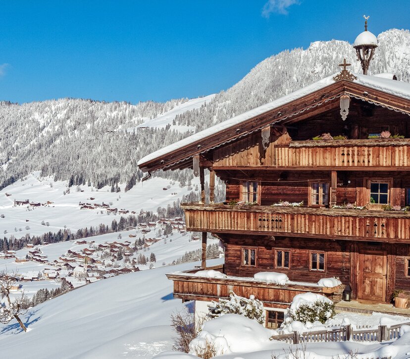 Auf dem Bild zu sehen ist die verschneite Winterlandschaft in Alpbach, im Vordergrund ein altes Bauernhaus
