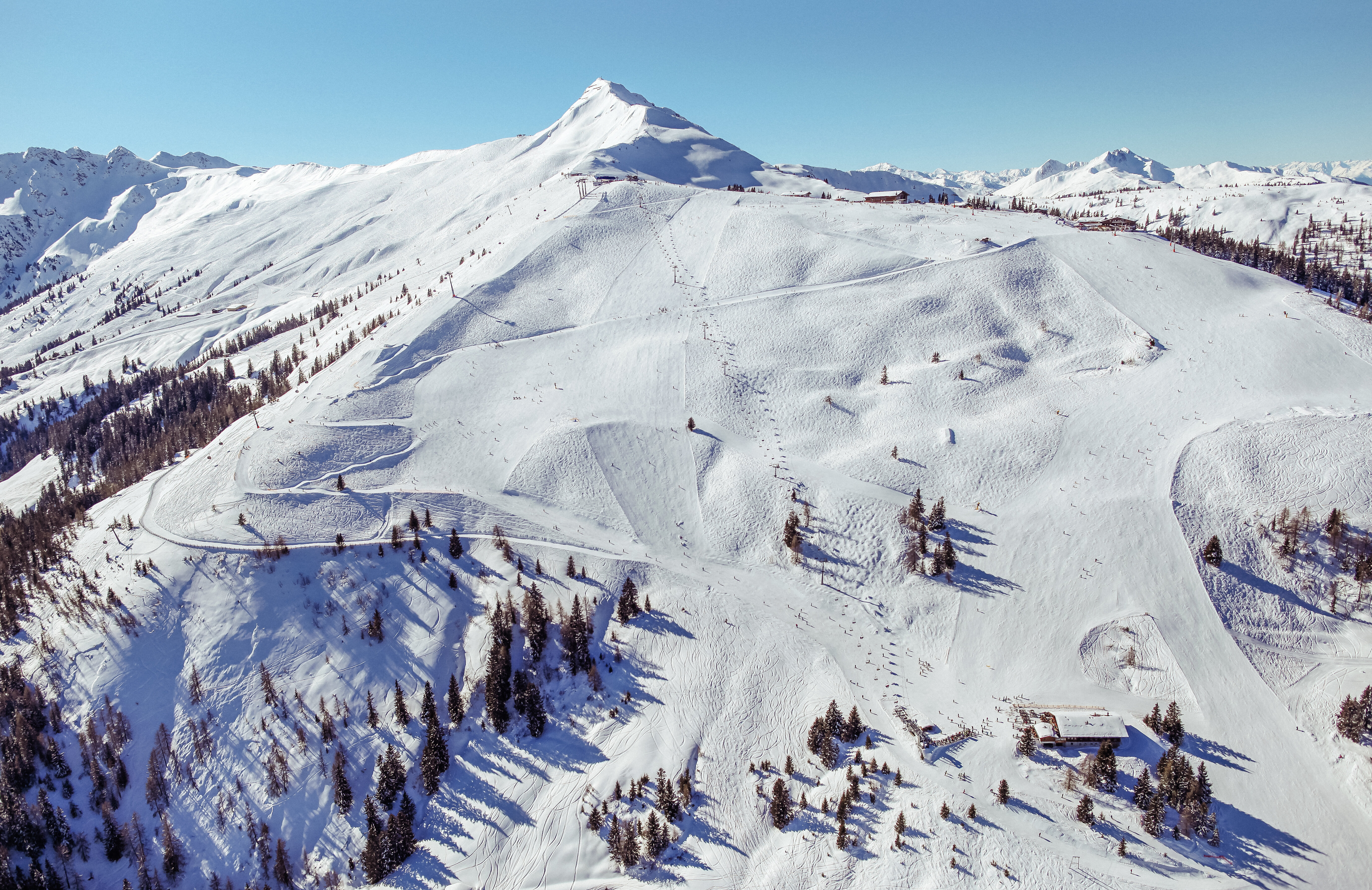 Eine Panoramaaufnahme vom Skigebiet Ski Juwel Alpbachtal Wildschönau, verschneite Winterlandschaft, Skilifte und das Wiedersberger Horn sind zu sehen 