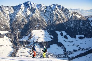 Ein Paar schaut von der frisch präparierten Piste aus hinunter nach Alpbach ins Tal. | © Alpbachtal Tourismus