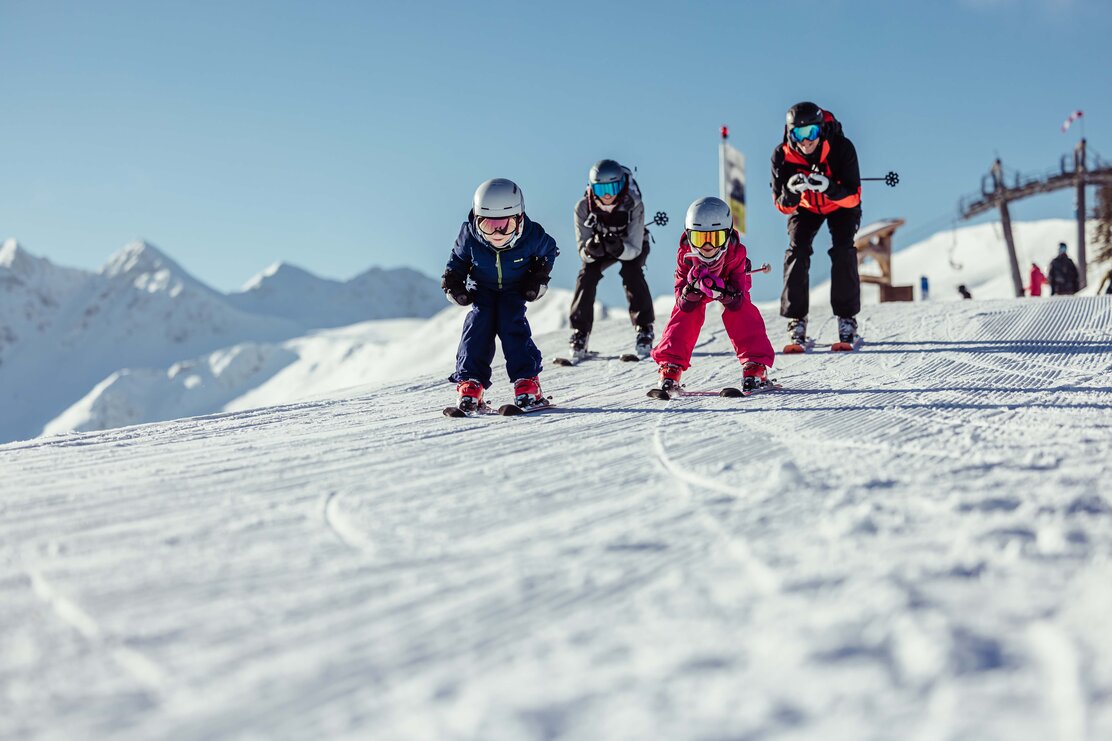 Eine Familie, bestehen aus Mutter, Vater, Tochter und Sohn, fahren gemeinsam, im Schuss, die Piste runter  | © Alpbachtal Tourismus | shootandstyle 