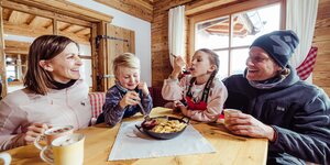 Skiurlaub mit Kindern im Alpbachtal | © Alpbachtal Tourismus | shootandstyle Eine Familie isst auf der Skihütte das typische Tiroler Gericht, Kaiserschmarrn | © Alpbachtal Tourismus | shootandstyle
