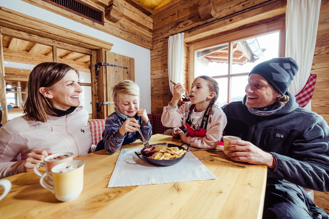 Skiurlaub mit Kindern im Alpbachtal  | © Alpbachtal Tourismus | shootandstyle  Eine Familie isst auf der Skihütte das typische Tiroler Gericht, Kaiserschmarrn | © Alpbachtal Tourismus | shootandstyle