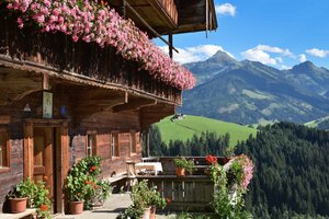 Ein Bauernhof im einzigartigen Alpbacher Baustil, am Balkon wunderschöne Blumen, im Hintergrund die Berglandschaft | © Alpbachtal Tourismus 