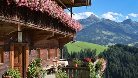 Ein Bauernhof im einzigartigen Alpbacher Baustil, am Balkon wunderschöne Blumen, im Hintergrund die Berglandschaft | © Alpbachtal Tourismus 
