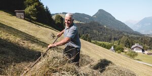 Feldarbeit in Reith i.A. | © Alpbachtal Tourismus | Mathäus Gartner Ein Bauer ist bei der Feldarbeit, mit einem Rechen platziert er das Heu für die Abholung am Scheffachberg in Reith i.A. | © Alpbachtal Tourismus | Mathäus Gartner