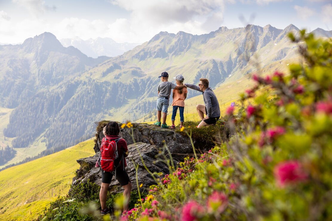 Eine Familie genießt die Aussicht auf einem Fels, während ihrer Wanderung auf dem Panoramaweg in Richtung Wiedersberger Horn  | © Alpbachtal Tourismus | shootandstyle 