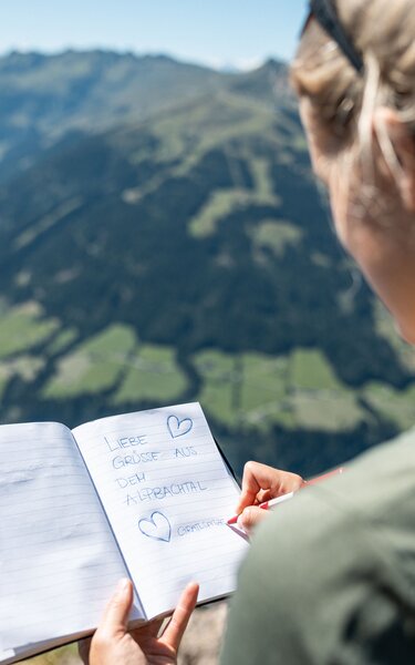 Gipfelbucheintrag Gratlspitze | © Alpbachtal Tourismus | shootandstyle Eine Frau trägt sich gerade ins Gipfelbuch Gratlspitze ein | © Alpbachtal Tourismus | shootandstyle