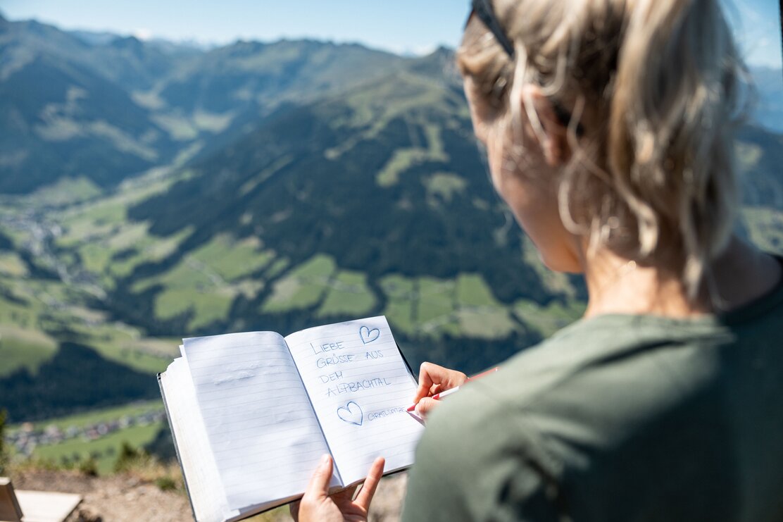 Eine Frau trägt sich gerade ins Gipfelbuch Gratlspitze ein  | © Alpbachtal Tourismus | shootandstyle 
