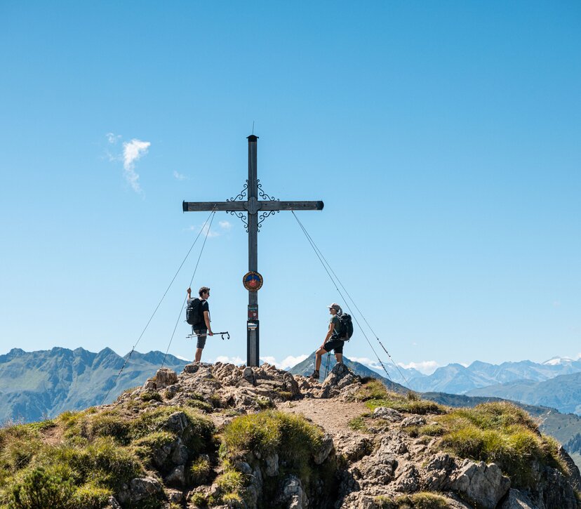 Ein Paar genießt gemeinsam den Gipfelsieg am Gipfelkreuz Gratlspitze im Alpbachtal  | © Alpbachtal Tourismus | shootandstyle 