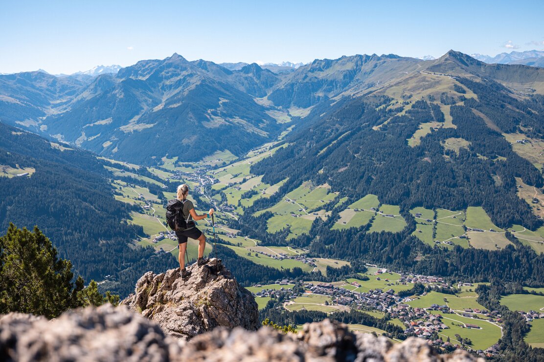 Eine Frau steht auf einem Fels auf dem Gipfel Gratlspitze und betrachtet die schöne Aussicht auf das Alpbachtal  | © Alpbachtal Tourismus | shootandstyle 