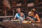 Hüttenjause auf der Farmkehralm in Inneralpbach | © Alpbachtal Tourismus | Mathäus Gartner Eine Familie isst genüsslich eine Brettljause auf der Farmkehralm in Inneralpbach | © Alpbachtal Tourismus | Mathäus Gartner