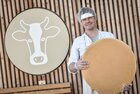 Alpbachtaler Heumilchkäserei Reith i.A. | © Alpbachtal Tourismus Ein Mann steht mit einem großem Leib Käse vor dem Logo der Alpbachtaler Heumilchkäserei in Reith i.A. | © Alpbachtal Tourismus