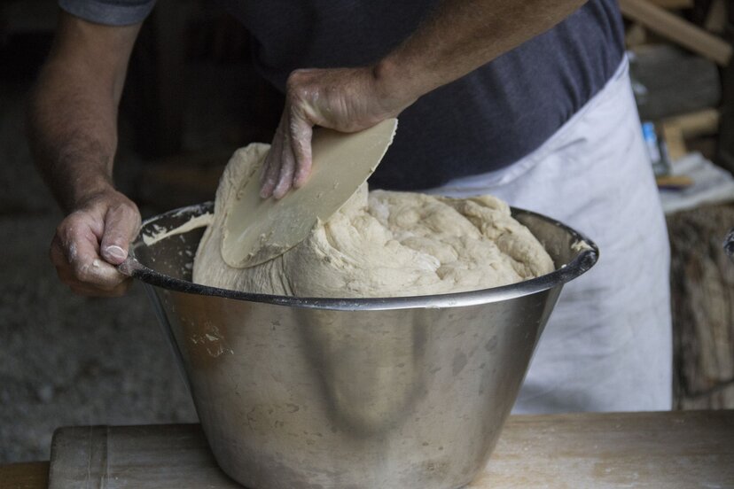 Bauernbrot Kulinarik | © Tirol Werbung Ein Mann knetet den Brotteig, welcher sich in einer Schüssel befindet | © Tirol Werbung