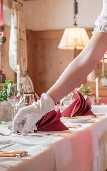 Service in der Fuggerstube | © Hotel Böglerhof Auf diesem Bild ist eine Frau im Dirndl, mit weißen Handschuhen beim Tisch eindecken zu sehen | © Hotel Böglerhof