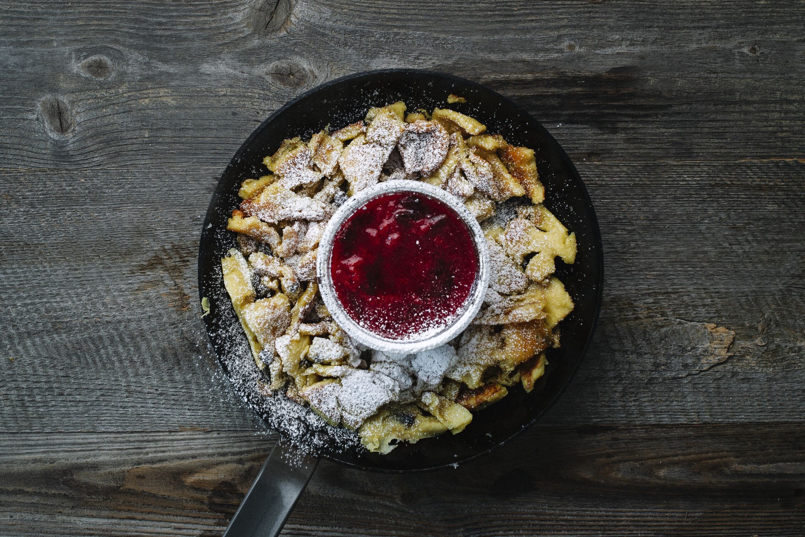 Eine Pfanne voller Kaiserschmarrn, in der Mitte befindet sich noch eine kleine Schüssel voller Preiselbeeren  | © Tirol Werbung | Kathrin Konschitzki