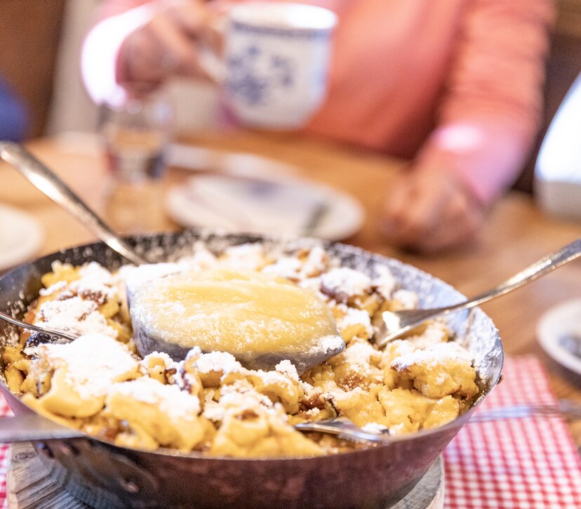 Eine Pfanne voller Kaiserschmarrn, in der  Mitte befindet sich eine Schüssel voller Apfelmus  | © Alpbachtal Tourismus | shootandstyle 