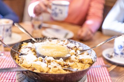 Eine Pfanne voller Kaiserschmarrn, in der  Mitte befindet sich eine Schüssel voller Apfelmus  | © Alpbachtal Tourismus | shootandstyle 