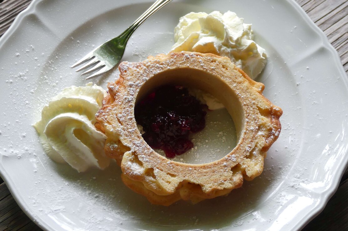Auf diesem Bild zu sehen ist ein Stück einer Prügeltorte mit Preiselbeermarmelade und Sahne  | © Kaiserhaus | Bernd Kregel