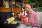 Schaubacken im Kaiserhaus in Brandenberg | © Alpbachtal Tourismus Familie Larch gerade beim Prügeltorten Schaubacken im Kaiserhaus in Brandenberg, beide lächeln in die Kamera, im Hintergrund der Gastgarten zu sehen | © Alpbachtal Tourismus