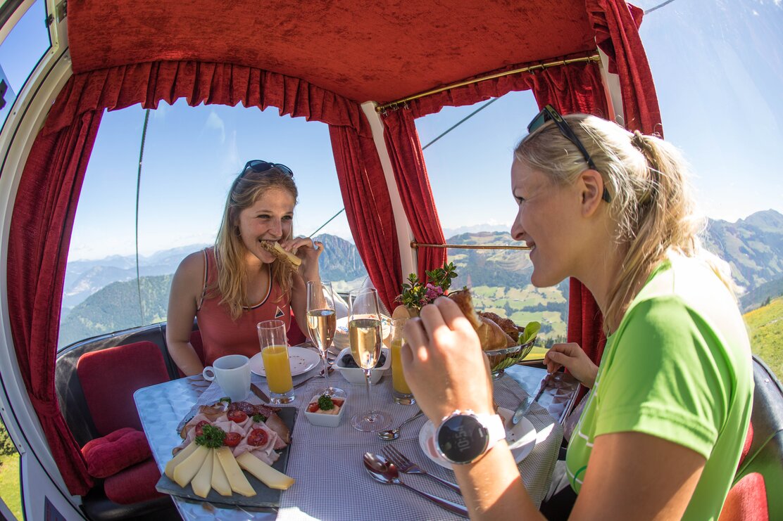 Zwei junge Frauen genießen ihr Frühstück in der Genussgondel der Alpbacher Bergbahnen  | © Alpbacher Bergbahnen | shootandstyle 