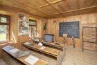 Schule im Museum Tiroler Bauernhöfe | © Alpbachtal Tourismus| Matthias Sedlak Auf dem Bild zu sehen ist eine alte Schule, im Museum Tiroler Bauernhöfe, mit einer großen Schiefertafel und alten Schulbänken, auf denen ein Mädchen sitzt | © Alpbachtal Tourismus| Matthias Sedlak