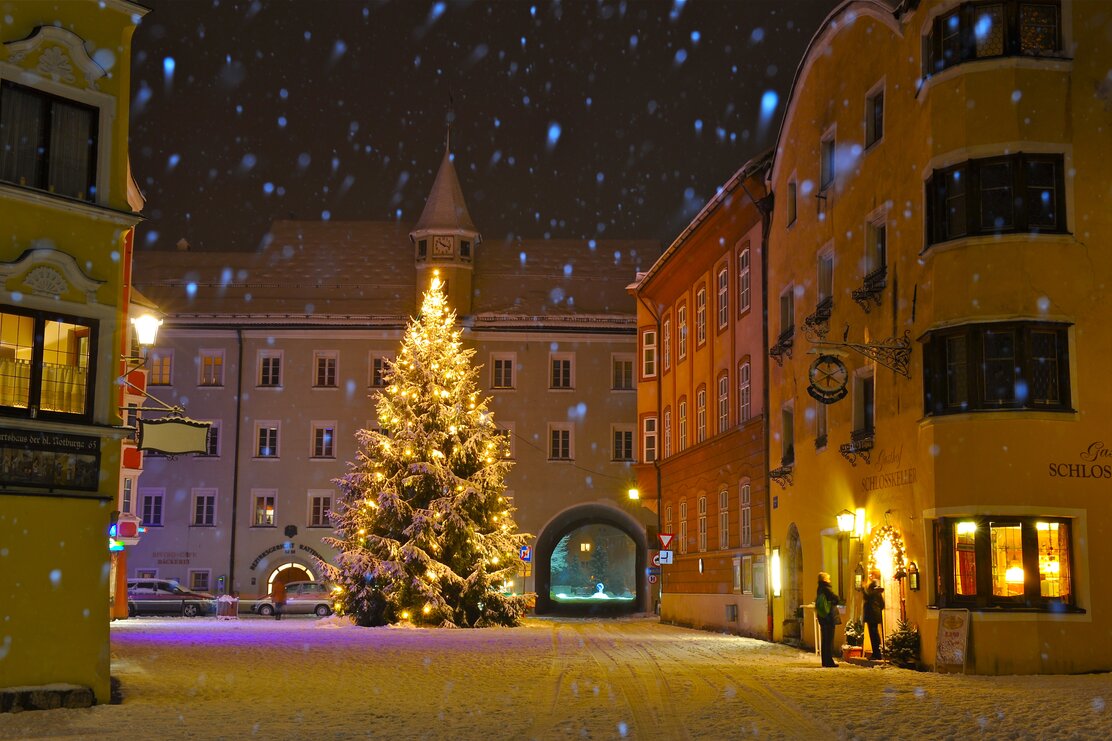 Die Stadt Rattenberg im Winter bei Nacht, inmitten der Stadt ein wunderschöner Christbaum, bedeckt von Schnee und hell erstrahlt von der Lichterkette  | © Bernhard Berger