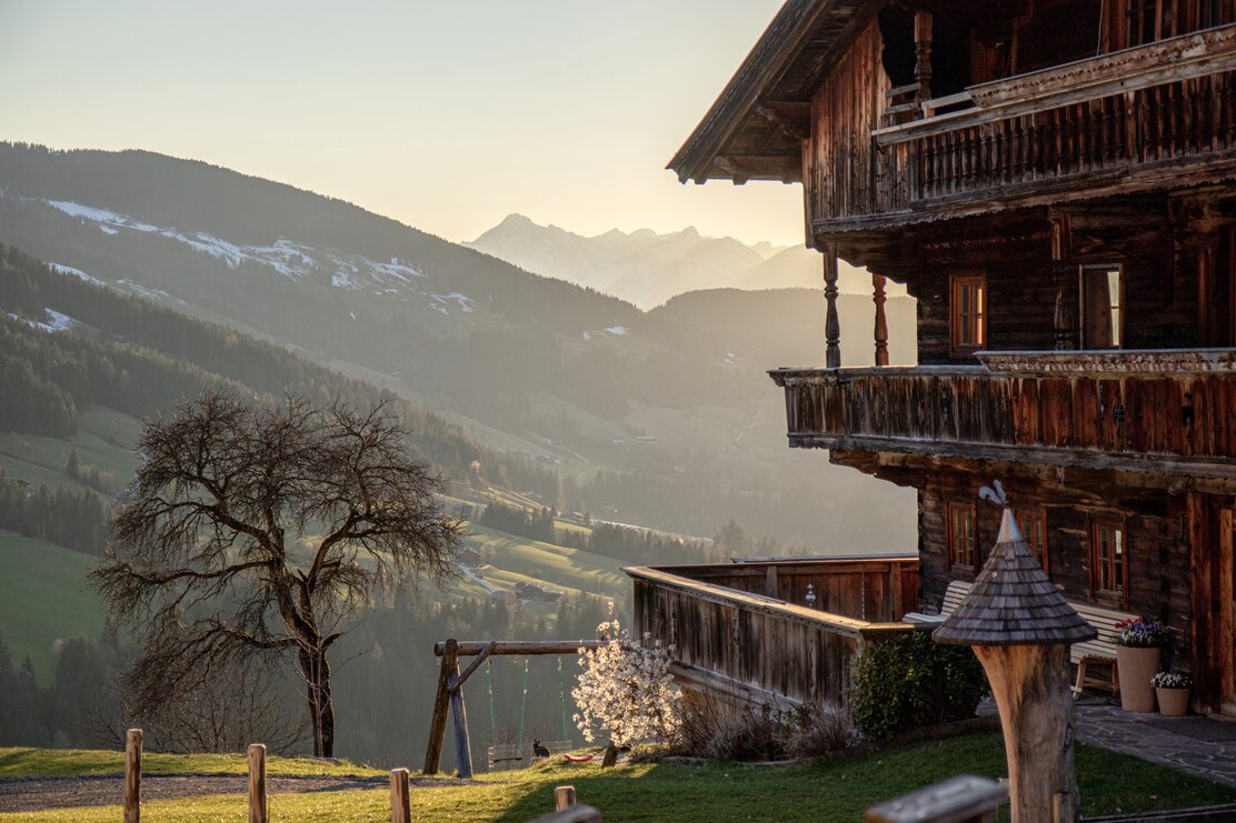 Bauernhaus in Alpbach im Frühling mit Ausblick auf die verschneiten Berge | © Maxime Foegle