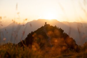 Zwei Personen stehen neben der Rastbank Gratlspitze, sie genießen den wundervollen Sonnenuntergang  | © Alpbachtal Tourismus  | Torsten Mühlbacher 