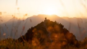 Zwei Personen stehen neben der Rastbank Gratlspitze, sie genießen den wundervollen Sonnenuntergang  | © Alpbachtal Tourismus  | Torsten Mühlbacher 