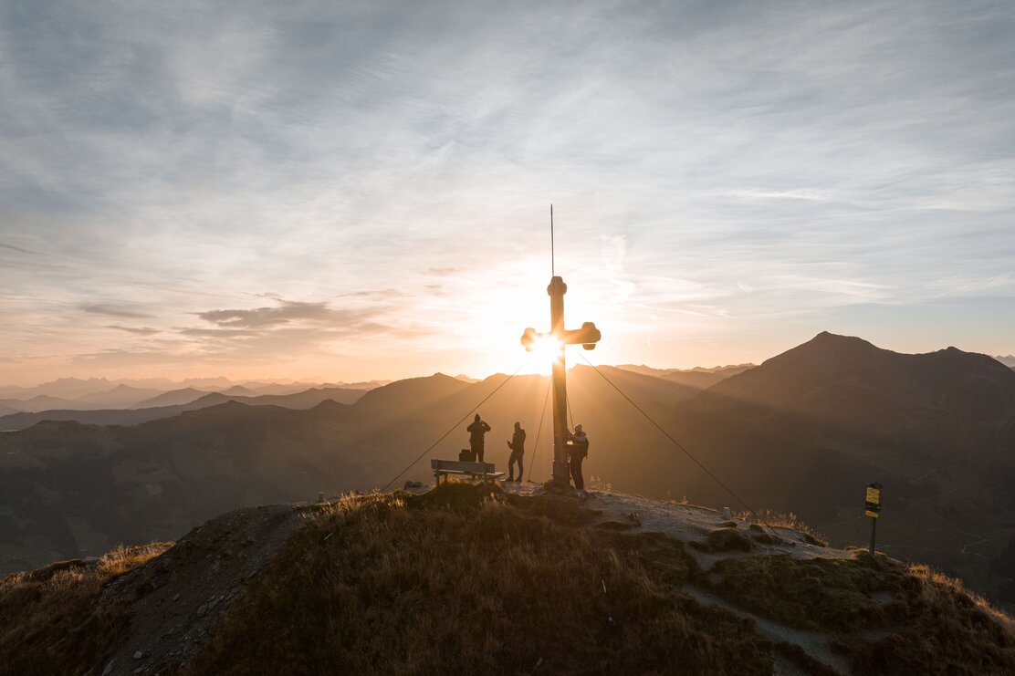 Eine Drohnenaufnahme vom Wiedersberger Horn Gipfelkreuz, die Sonne geht gerade unter  | © Alpbachtal Tourismus | shootandstyle 