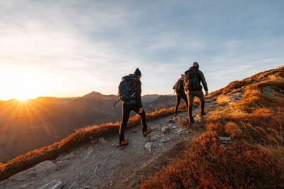 Drei Männer wandern im Herbst in Richtung Wiedersberger Horn, die Sonne geht unter und es herrscht herbstliche Stimmung in der Natur  | © Alpbachtal Tourismus | shootandstyle 