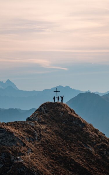 Auf diesem Bild zu sehen, das Gipfelkreuz der Sagtaler Spitze in Alpbach, auf dem Gipfel befinden sich drei Personen, im Hintergrund die schöne Bergkulisse | © Alpbachtal Tourismus | shootandstyle 