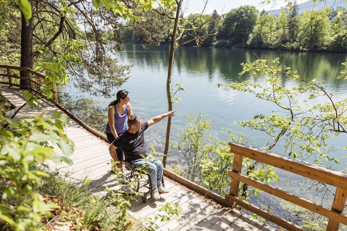 Eine Frau schiebt ihren Mann entlang des Barrierefreien Wanderweges am Reintalersee in Kramsach.  | © Alpbachtal Tourismus | shootandstyle 