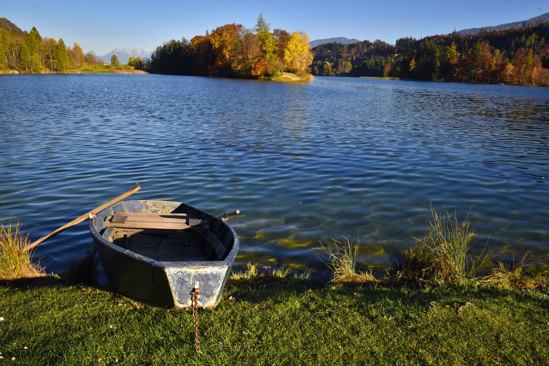 Auf diesem Bild zu sehen ist der Reintalersee in Kramsach, im Vordergrund liegt ein kleines Paddelboot am Seeufer  | © Alpbachtal Tourismus | Gabriele Grießenböck 