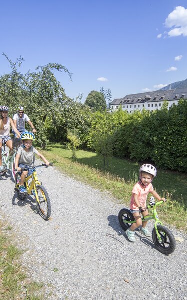 Familienradtour am Inn entlang | © Alpbachtal Tourismus | Matthias Sedlak Eine vierköpfige Familie macht gemeinsam eine Radtour am Inn entlang, mit Blick auf das damalige Kloster in Rattenberg | © Alpbachtal Tourismus | Matthias Sedlak