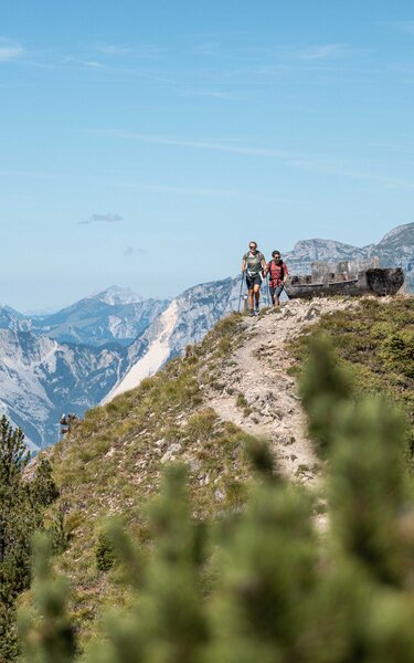 Wanderurlaub zu zweit im Alpbachtal | © Alpbachtal Tourismus | shootandstyle Ein Paar wandert gemeinsam an einer Rastbank am Berg Gratlspitze vorbei | © Alpbachtal Tourismus | shootandstyle