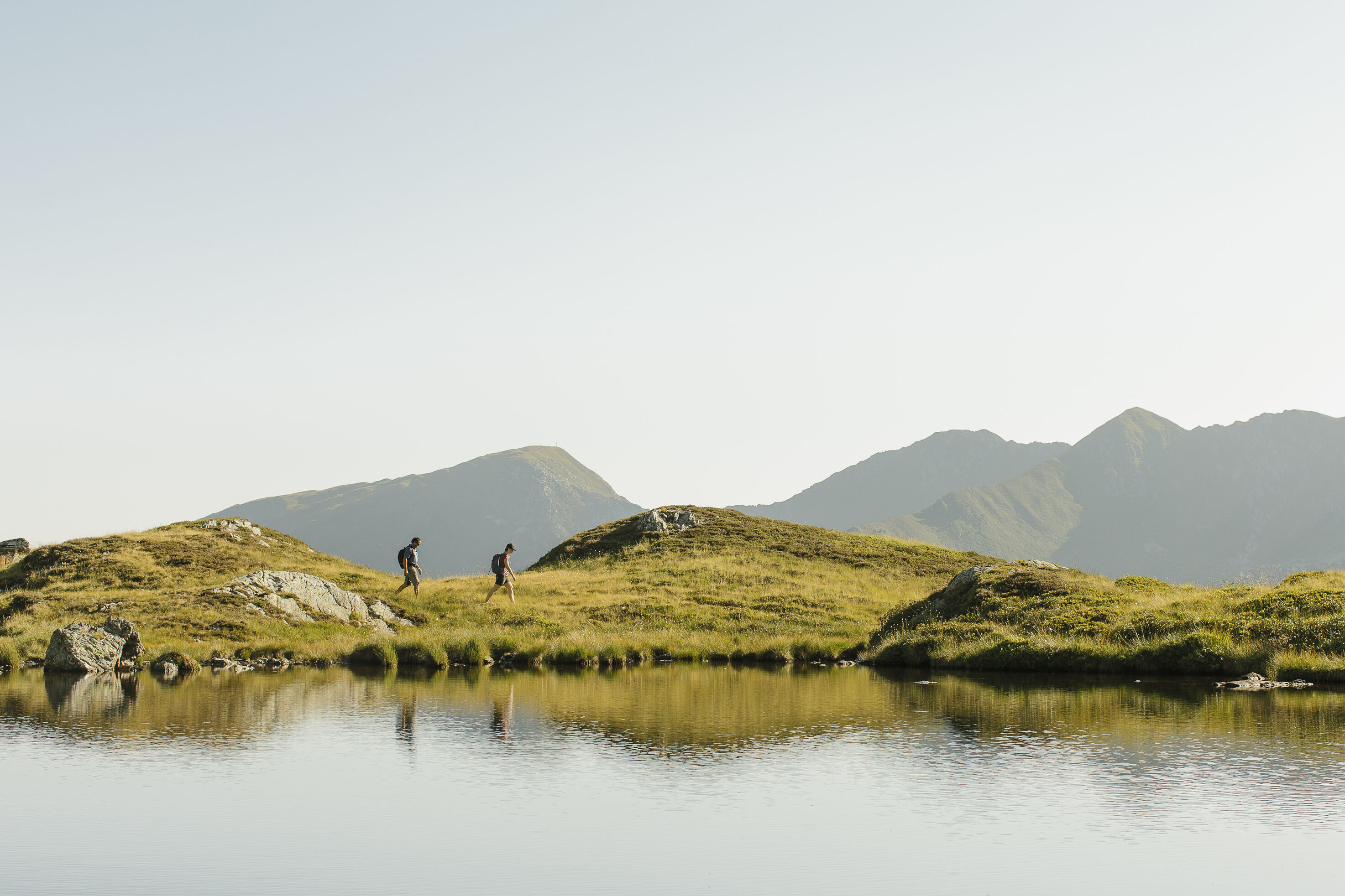 Ein Paar wandert entlang eines Sees, in Richtung des Gipfels Torkopf | © Alpbachtal Tourismus | E. Holzknecht 
