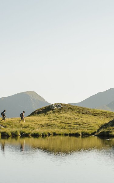 Sommerwanderung Torkopf | © Alpbachtal Tourismus | E. Holzknecht Ein Paar wandert entlang eines Sees, in Richtung des Gipfels Torkopf | © Alpbachtal Tourismus | E. Holzknecht