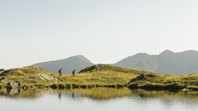 Ein Paar wandert entlang eines Sees, in Richtung des Gipfels Torkopf | © Alpbachtal Tourismus | E. Holzknecht 