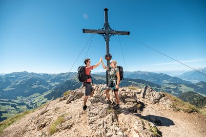 Ein Paar steht am Gipfelkreuz der Gratlspitze und freut sich über die Aussicht  | © Alpbachtal Tourismus | shootandstyle 