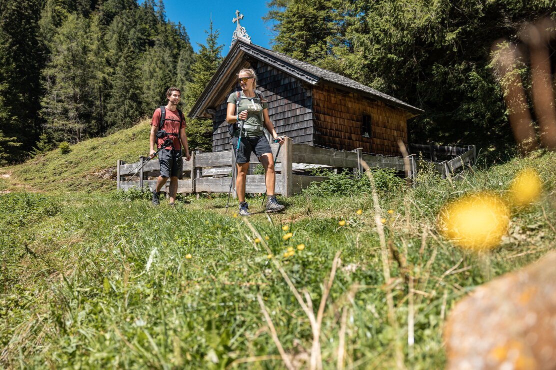 Ein paar wandert durch das Hösljoch, vorbei an der Höslkapelle in Alpbach | © Alpbachtal Tourismus | shootandstyle