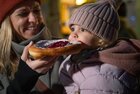 Advent in Tirol | © Tirol Werbung | Heinzlmeier Bert Eine Mutter lässt ihre kleine Tochter vom Tiroler Kiachl abbeißen | © Tirol Werbung | Heinzlmeier Bert
