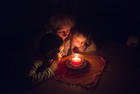 Zwei Kinder und ihre Oma vor einer Kerze im Dunkeln | © Tirol Werbung_Wiedenhofer Martina_Zirl