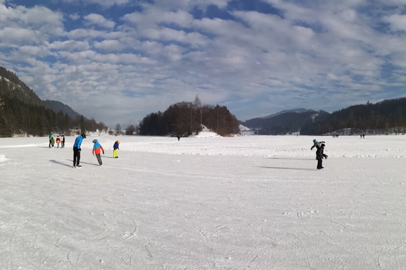 Eislaufen am Reintalersee in Kramsach | © Alpbachtal Tourismus Auf diesem Bild zu sehen sind einige Menschen, welche gerade auf dem eingefrorenen Reintalersee eislaufen | © Alpbachtal Tourismus