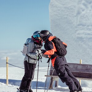 Auf diesem Bild ist zu sehen, wie sich ein Paar küsst, im Hintergrund sieht man ein Schneeherz, welches im Ski Juwel Alpbachtal Wildschönau platziert wurde  | © Alpbachtal Tourismus | shootandstyle 