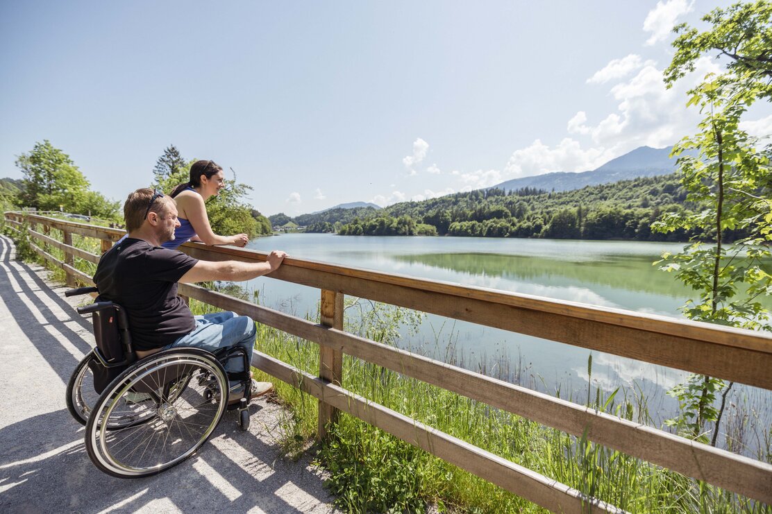 Ein Mann im Rollstuhl genießt gemeinsam mit seiner Frau die schöne Aussicht am Reintalersee in Kramsach  | © Alpbachtal Tourismus | shootandstyle 