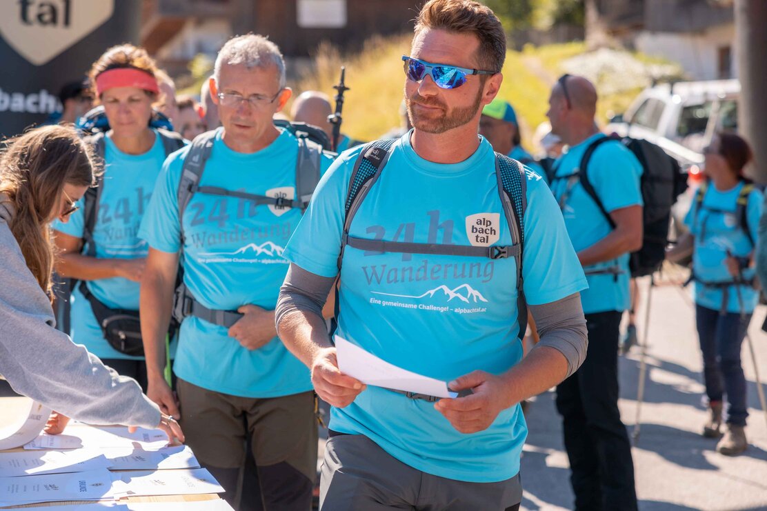 Auf diesem Bild zu sehen sind einige Teilnehmer der 24h Wanderung bei der Anmeldung, sie tragen das blaues 24h Wanderung T-Shirt  | © Alpbachtal Tourismus | shootandstyle 