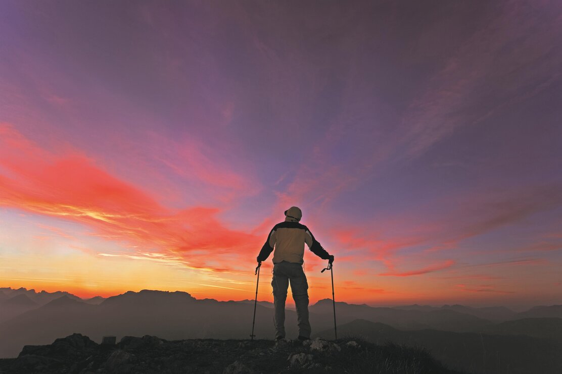 Ein Mann steht auf der Gratlspitze und genießt den farbenfrohen Sonnenaufgang  | © Alpbachtal Tourismus | Bernhard Berger 